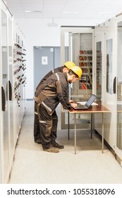 Two maintenance engineers inspect relay protection system with laptop computer. Bay control unit. Medium voltage switchgear - Shutterstock ID 1055318096