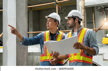 Two Male Architect In Construction Site And Point To Something With Blueprint Paper With Strategy Concept,Foreman With Building Interior Cement House Background,Builder And White Hard Hat With Vest.