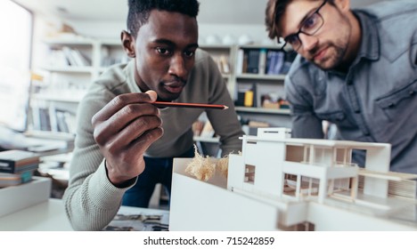 Two male architects in office discussing construction project. Young men working together on new building model. - Powered by Shutterstock