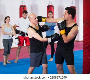 Two Male Athletes In Sportswear Practicing Boxing Sparring In Gym