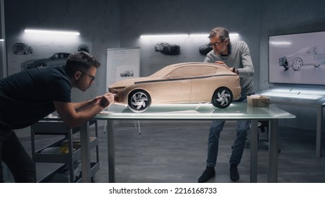 Two male automotive designers creating model of car in modern car design studio. One sculpting with plasticine clay, other working at the touch table. Future design of eco friendly electric car. - Powered by Shutterstock