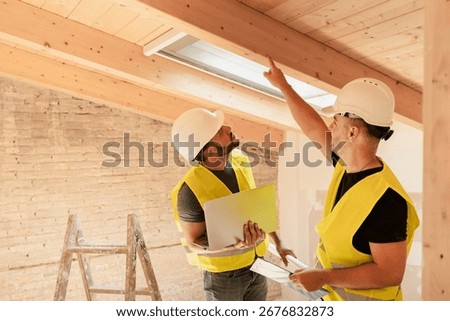 Two male Construction workers using laptop inspecting wooden beams in building renovation project