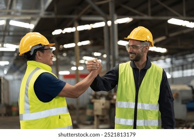 Two male engineer join hands together in industry factory. Finished, completed work concept