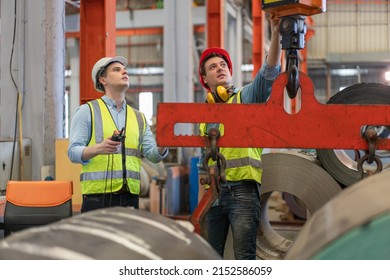 Two male engineers wear safety vest with helmet checking and control factory overhead crane.Professional technicians in industrial machinery - Powered by Shutterstock