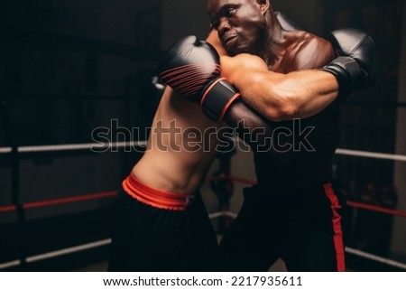 Two male fighters fighting with gloves in a boxing ring. Two athletic young men having a boxing match in a gym.