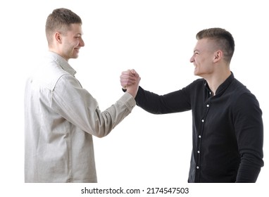 Two Male Friends In Casual Closes Greeting Each Other With A Handshake Isolated On White Background