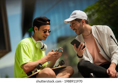 Two Male Friends Are Dicussing Something While Looking At Their Phones