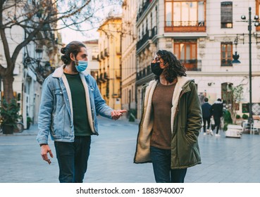 Two Male Friends With Masks and Long Hair Having a Conversation While Walking in The Street City Center - Powered by Shutterstock