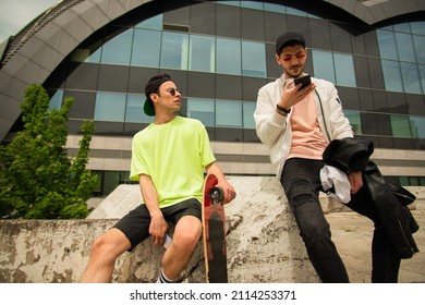 Two Male Friends Are Sitting On The Wall While Talking