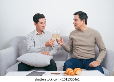 Two male friends are smiling and clanging glasses of champagne or wine - Shutterstock ID 1011320461