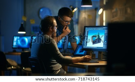 Two Male Game Developers Discuss Game Level Drawing, One Uses Graphic Tablet. They Work Late at Night in a Loft Office.