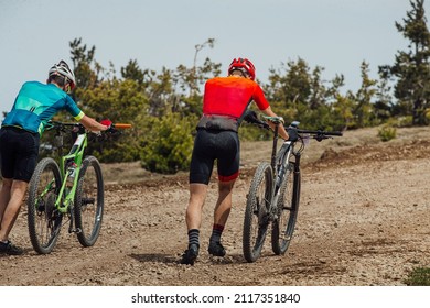 Two Male Go Uphill Trail With Their Mountain Bikes