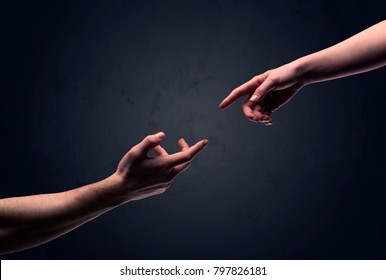 Two male hands reaching out to one another, almost touching, in front of dark clear empty background wall concept - Shutterstock ID 797826181