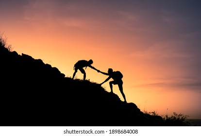 Two male hikers helping each other climb up a mountain. Teamwork and perseverance.  - Powered by Shutterstock