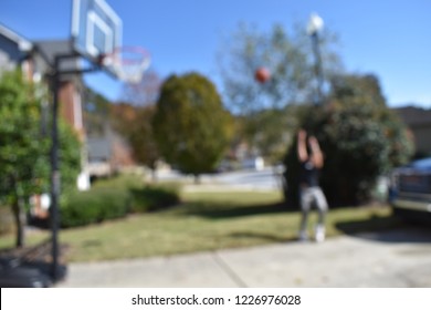 Two Male Kids Playing Basketball In A Driveway With Some Cars In The Background. Some Shots Are Just Of The Basketballs And Net.