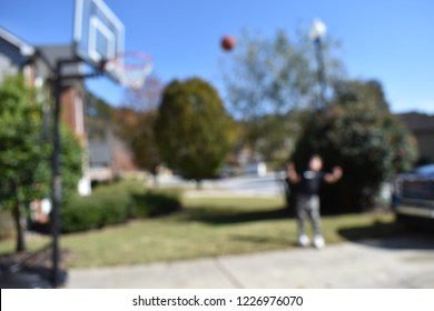 Two Male Kids Playing Basketball In A Driveway With Some Cars In The Background. Some Shots Are Just Of The Basketballs And Net.