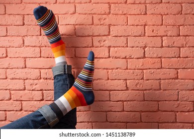 two male legs in colored socks leaning brick wall  concept  copy space