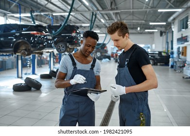 Two Male Mechanics Talking In Car Service