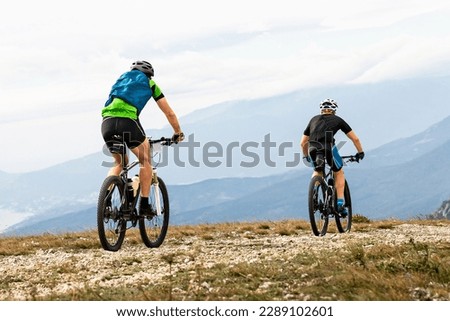 two male mountainbiker riding together sports cycle on mountainous terrain travelling cycling