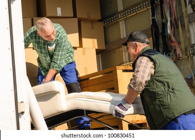 Two Male Movers Putting Furniture And Boxes  In Moving Truck