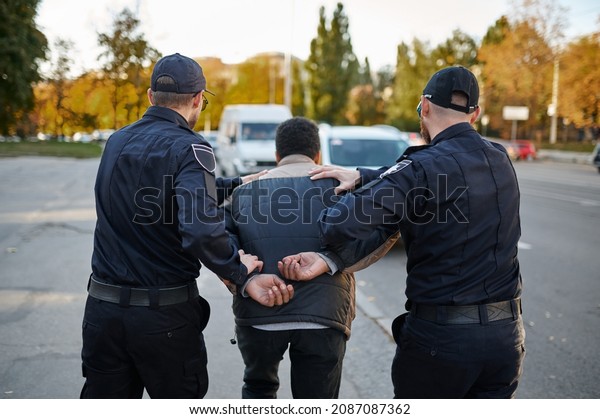 Two male police\
officers arrest young man