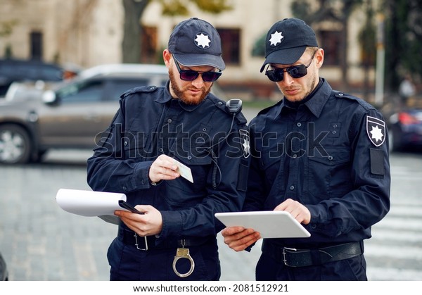 Two male police\
officers inspect car\
parking