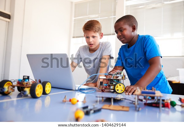 Two Male Students Building And\
Programing Robot Vehicle In After School Computer Coding\
Class