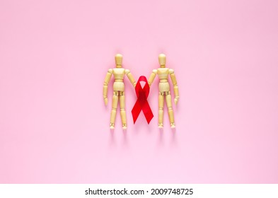 Two Male Wooden Model Holding Red Ribbon For Minimal Safe Sex, World Sexual Health And Aids Day Concept.