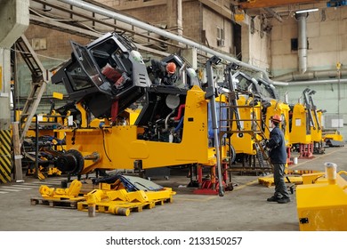 Two male workers of modern industrial plant or repairmen checking efficiency of huge construction machines in workshop - Shutterstock ID 2133150257