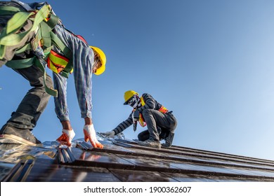Two Male Workers Wearing Safety Clothes Installing The Roof Tile House That Is A Ceramic Tile Roof On The Construction Site