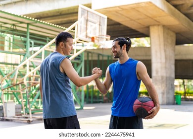 Two man basketball players shaking hand after playing one on one streetball match on outdoors court under highway in the city. Fair game competition, sportsmanship and outdoor sport training concept. - Powered by Shutterstock