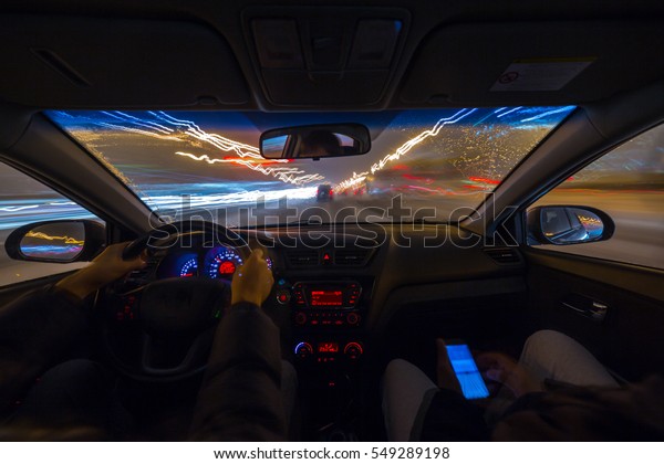Two man in a car\
moves at fast speed at the whinter night. Blured road with lights\
with car on high speed.