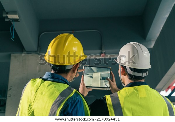 Two Man Civil Engineer and\
Contractor working in construction site. Team Architect working use\
BIM technology and digital construction application on digital\
tablet.