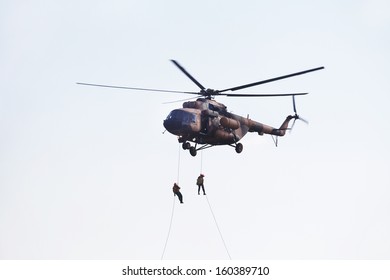 Two man climb from helicopter down a rope