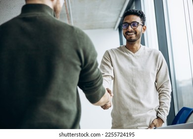 Two man colleagues shaking hands at the office - Shutterstock ID 2255724195