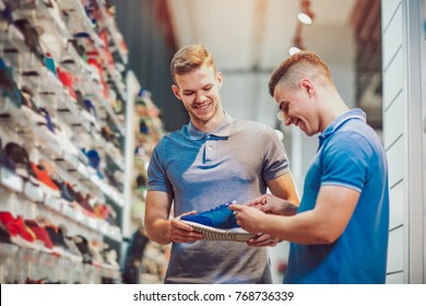 Two Man Deciding On New Sports Shoes In Sports Store