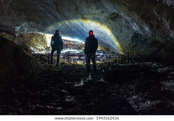 Two man exploring\
dark cave with light headlamp underground. Cave Ledenjaca in Bosnia\
and Herzegovina.
