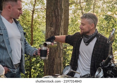 Two man friends of motorcyclists bikers on motorcycles drinking tea from a thermos on the side of the road and talking - Powered by Shutterstock