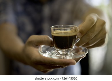Two Man Hand  Hold A Clear Cup Of Coffee. Cup Of  Black Hot  Coffee Ready To Serve .