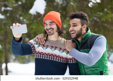 Two Man Hold Smart Phone Camera Taking Selfie Photo Snow Forest Mix Race Couple Outdoor Winter Pine Woods - Powered by Shutterstock