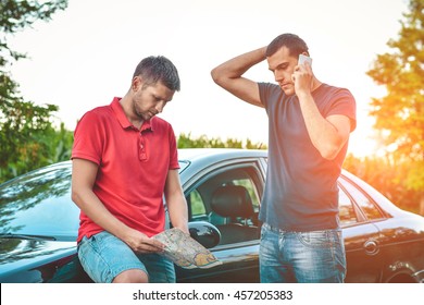 Two Man Lost In The Woods, One Uses Mobile Phone, Another Uses Map. Beauty Of Travelling. Hitchhiking Concept.