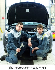 Two Man Mechanics Working Under The Hood Of A Car