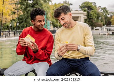 two man multiracial friends eating sandwich outdoors - Powered by Shutterstock