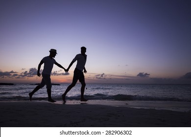 Two man running on the beach holding hands, at sunset. Isla Mujeres, Mexico. - Powered by Shutterstock