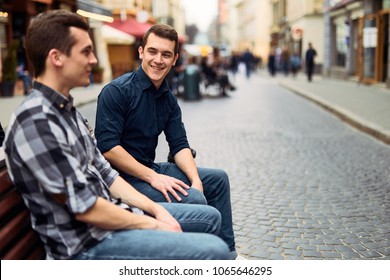 Two man sit on bench and talk on the street  - Powered by Shutterstock