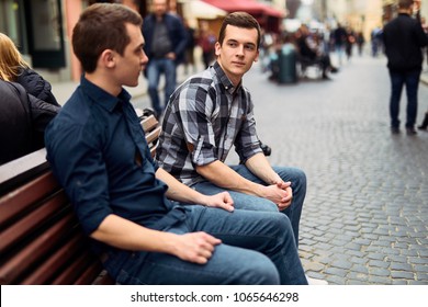 Two man sit on bench and talk on the street  - Powered by Shutterstock