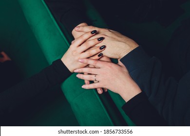 two man and three women holding hands on a table implying a polyamory relationship or love triangle.