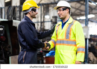 Two Man Worker Hand Shake At Industrial Factory Wearing Uniform And Hard Hats And Mechanical Repair.  Engineer Operating  Lathe Machinery