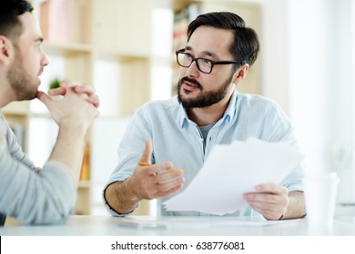 Two Managers Discussing Financial Documents At Meeting