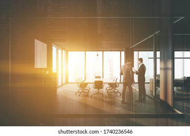 Two Managers Talking In Modern Meeting Room With Gray And Glass Walls, Wooden Door And Long Conference Table With Black Chairs. Concept Of Leadership. Toned Image Double Exposure